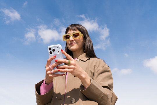 Traveller checking her phone under a clear sky